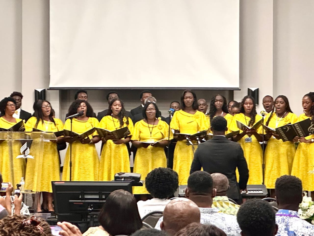 The Berean Fellowship Choir singing together on stage in yellow robes